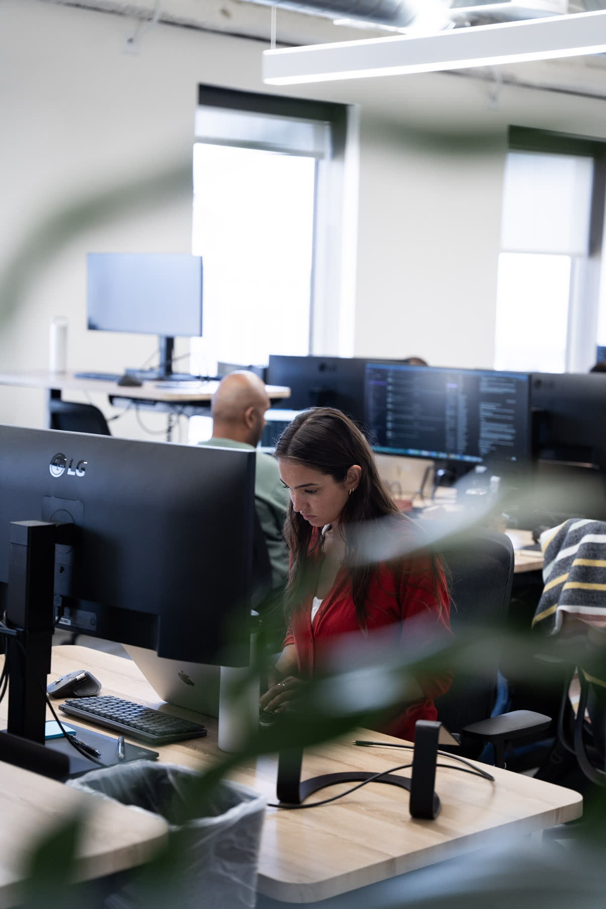 Teammate focused at her desk, seen through an office plant